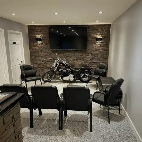 The Car Doctor+ customer lounge: a stone wall, a TV and a Harley-Davidson